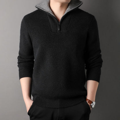 Person wearing a black sweater with a gray collar against a gray background