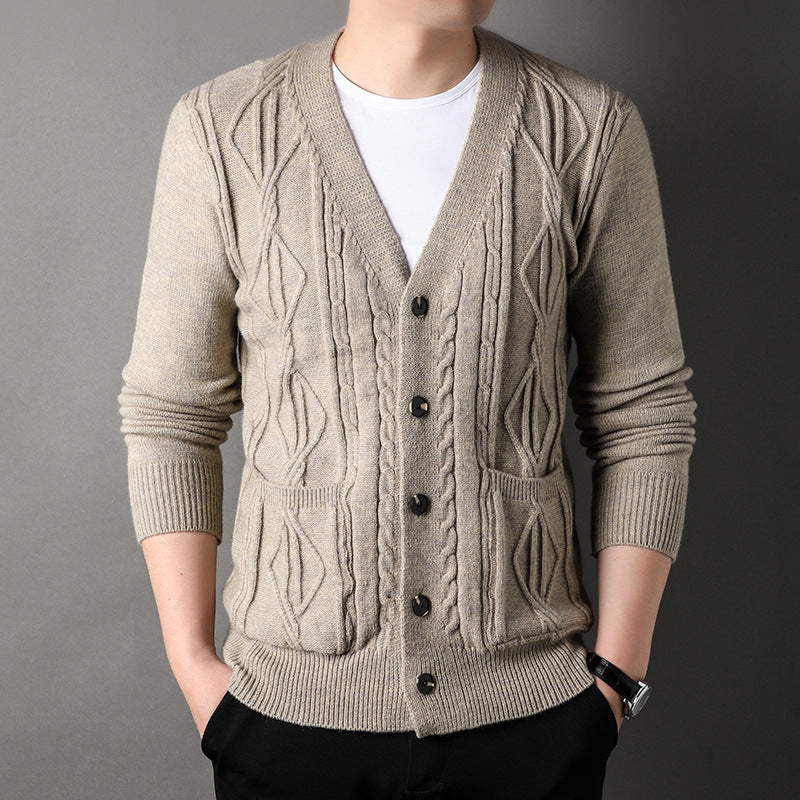 Man wearing a beige cable knit cardigan over a white shirt on a gray background