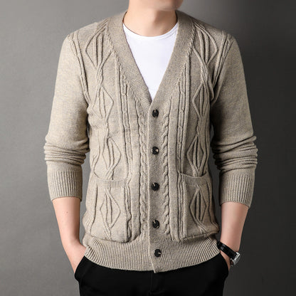 Man wearing a beige cable knit cardigan over a white shirt on a gray background