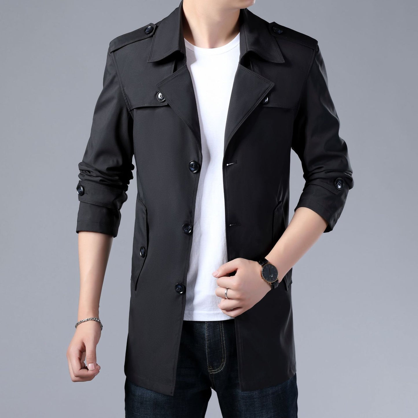 Black trench coat worn by a person on a gray background