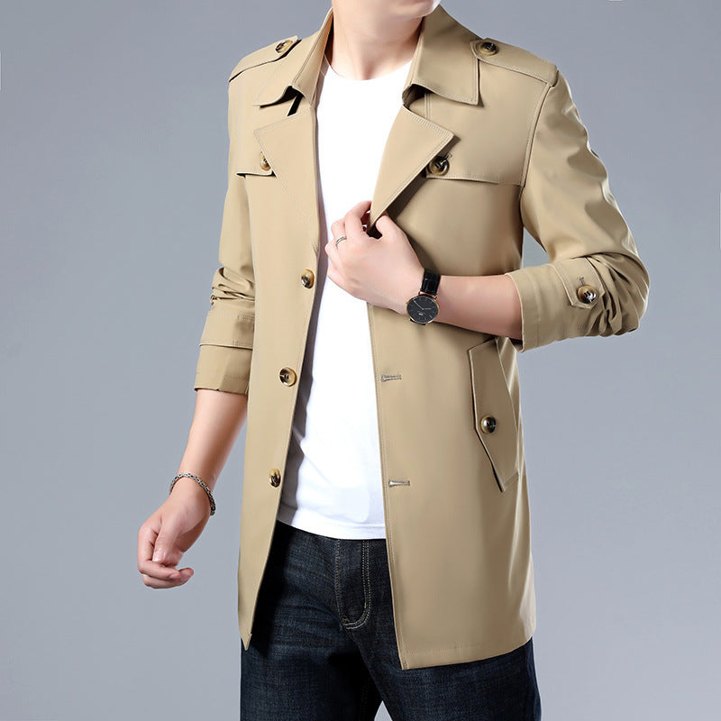 Man wearing a beige trench coat on a gray background