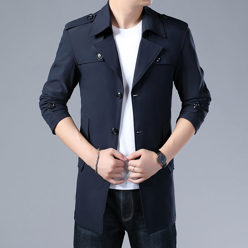 Man wearing a navy blue trench coat on a gray background